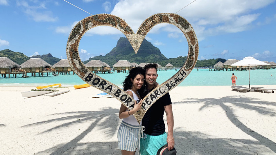 Honeymooners in front of Heart shaped sign on the beach at Pearl Resort in Bora Bora