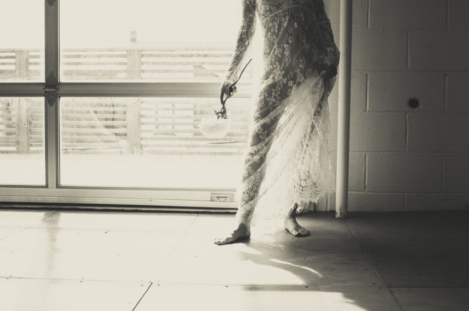 Black and white photo of woman's feet in front of window in white sheer lace