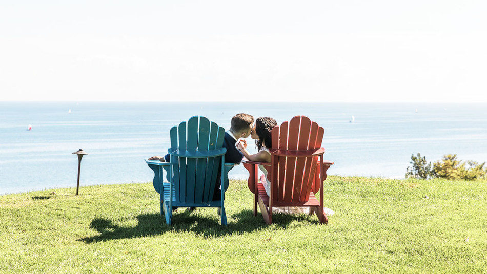 Bride and Groom kissing on muskoka chairs at Toronto Hunt Club in front of Lake ontario